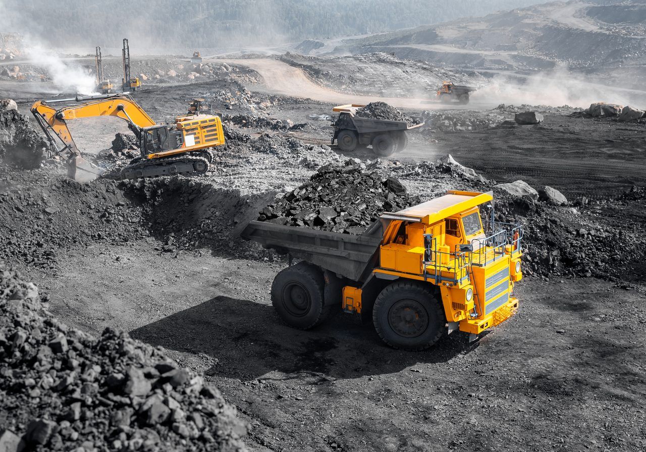 Excavator and haul truck loading coal at an open-pit mine